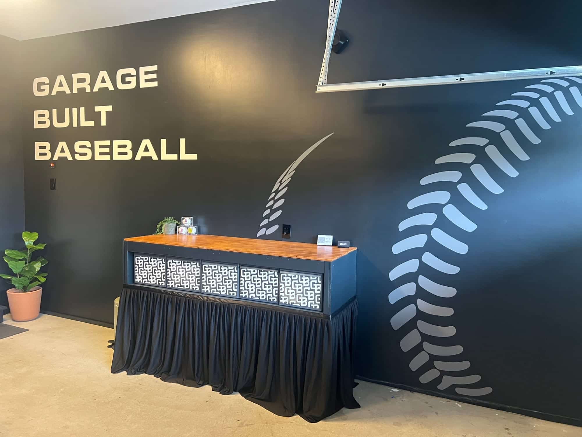 Inside the Garage Built Baseball garage — painted logo wall with a giant baseball-stitch mural