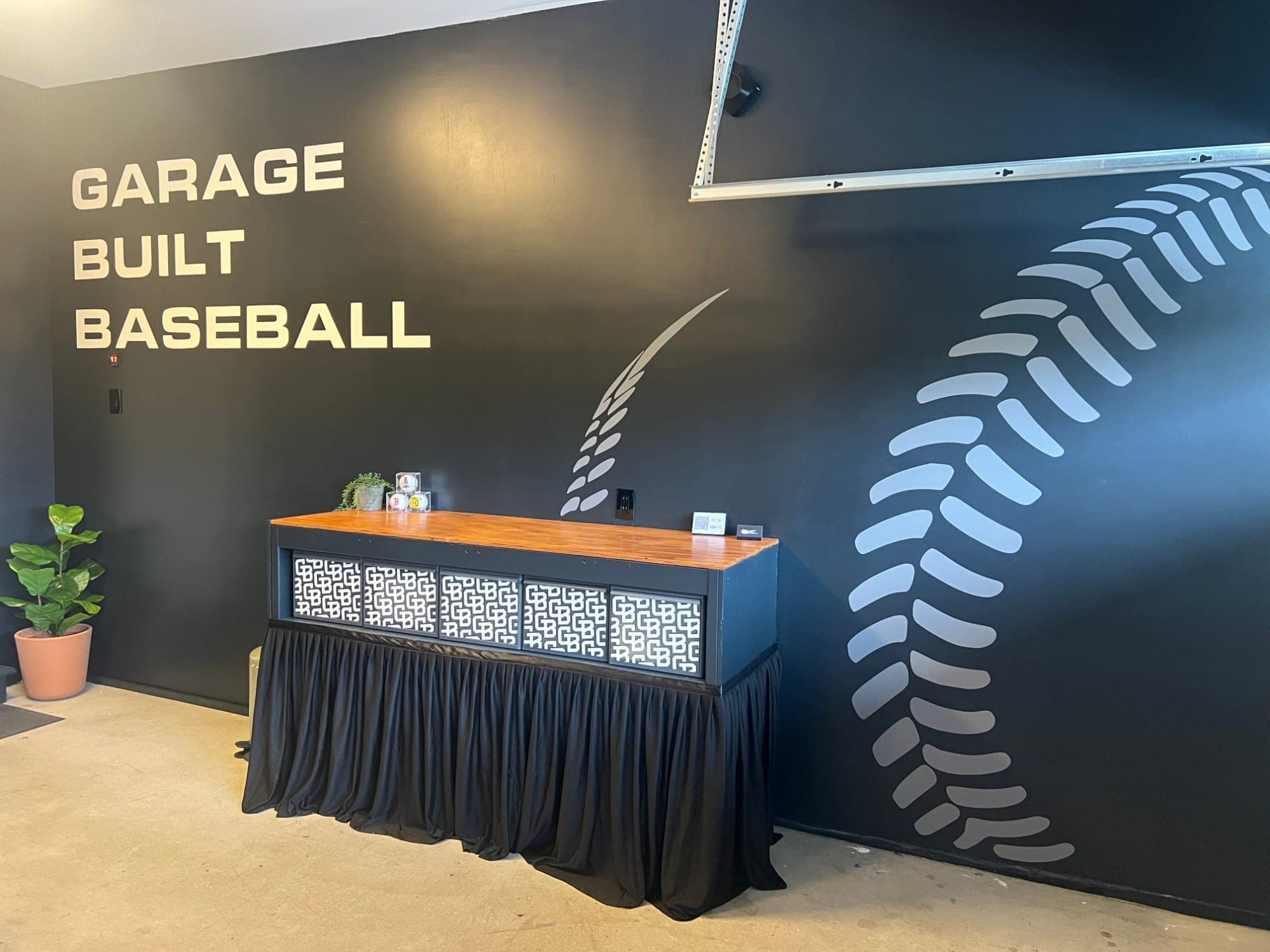 Inside the Garage Built Baseball garage — painted logo wall with a giant baseball-stitch mural