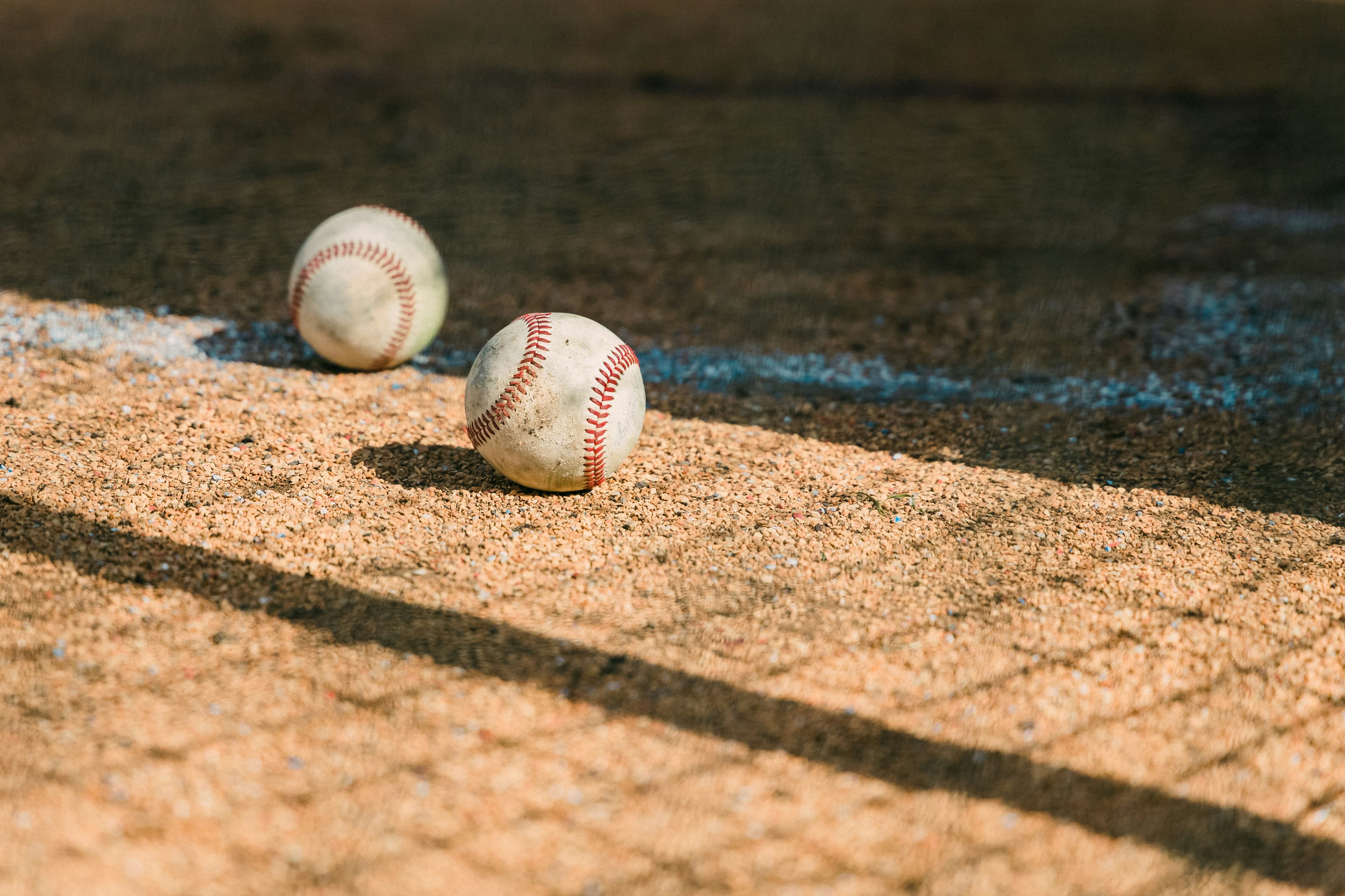 Two baseballs on warm infield clay