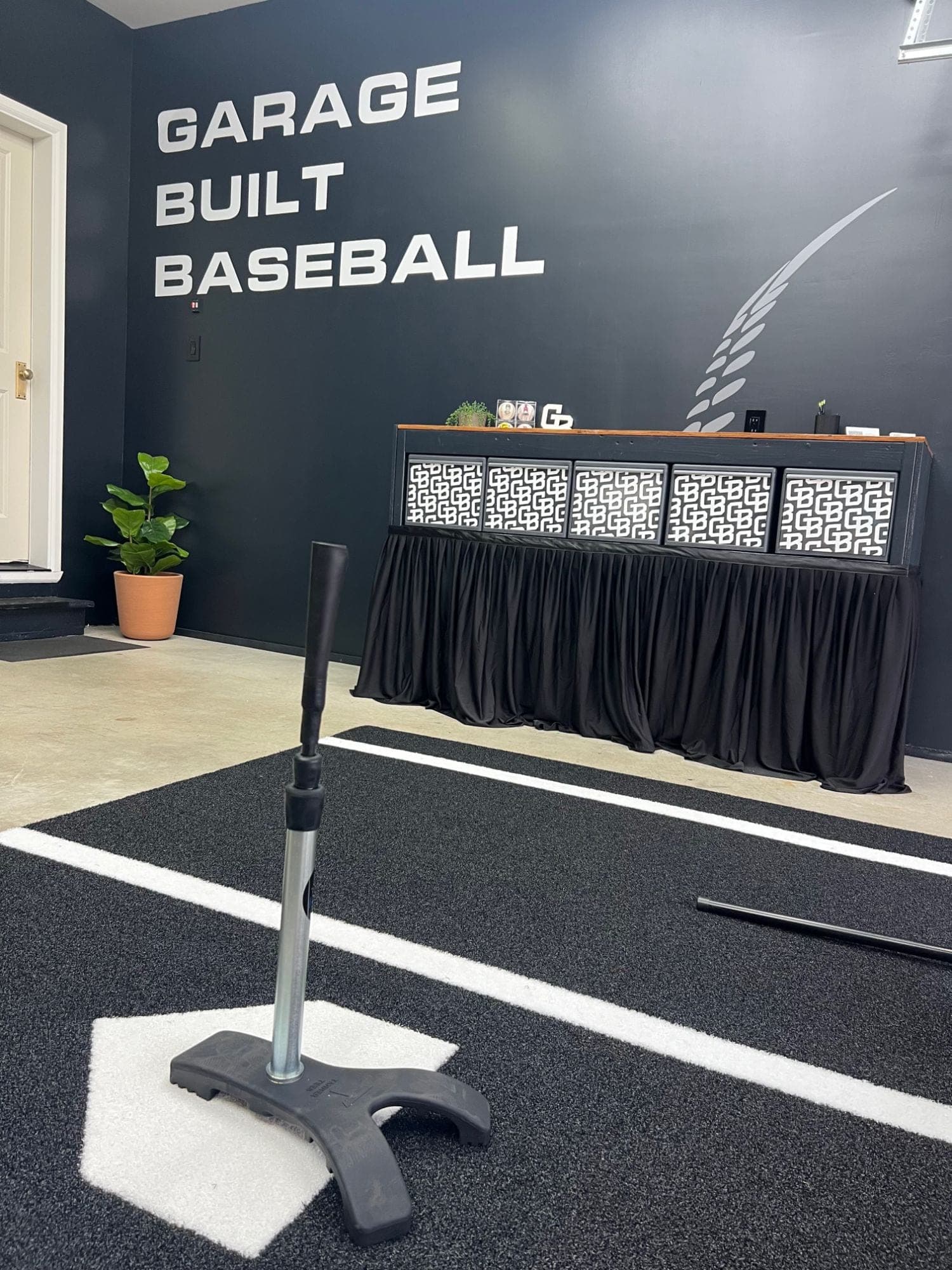 Batting tee on a home plate mat inside the Garage Built Baseball garage